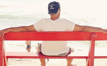 Rentner sitzt auf einer Bank am Strand und Meer