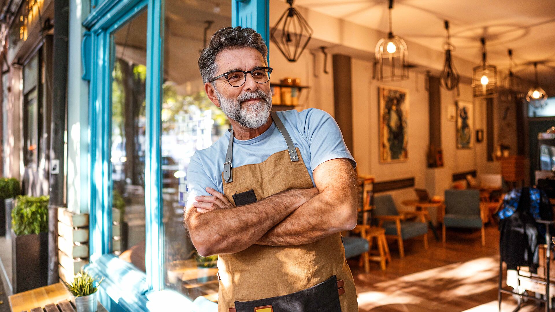 Ladenbesitzer lehnt lächelnd an der Eingangstür seines Lokals und schaut auf die Straße 