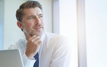 Rechtsschutz für Selbstständige Mann sitzt im Büro und guckt aus dem Fenster