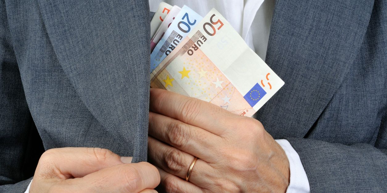 Steuerhinterziehung Person steckt Geld in die Jacke