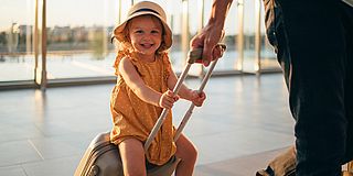 Kinderreisepass abgeschafft - Kind sitzt auf Reisekoffer