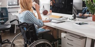 Schwerbehinderte Frau im Rollstuhl am Arbeitsplatz