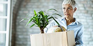 Kündigungsschutz ab 55 Jahren: ältere Frau mit Karton im Arm