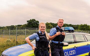 Polizeibeamte stehen vor einem Polizeifahrzeug