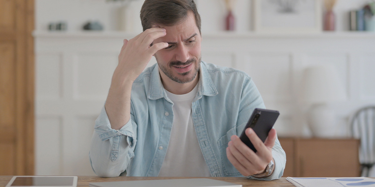 Mann blickt nachdenklich auf sein Smartphone