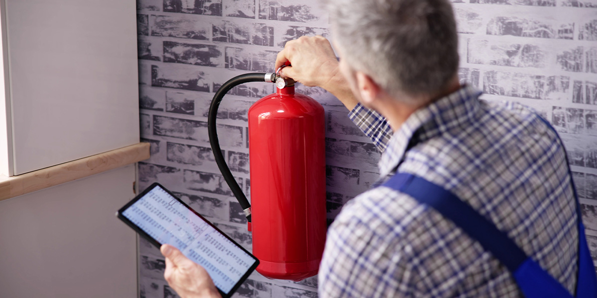 Handwerker überprüft Feuerlöscher der an einer Wand hängt