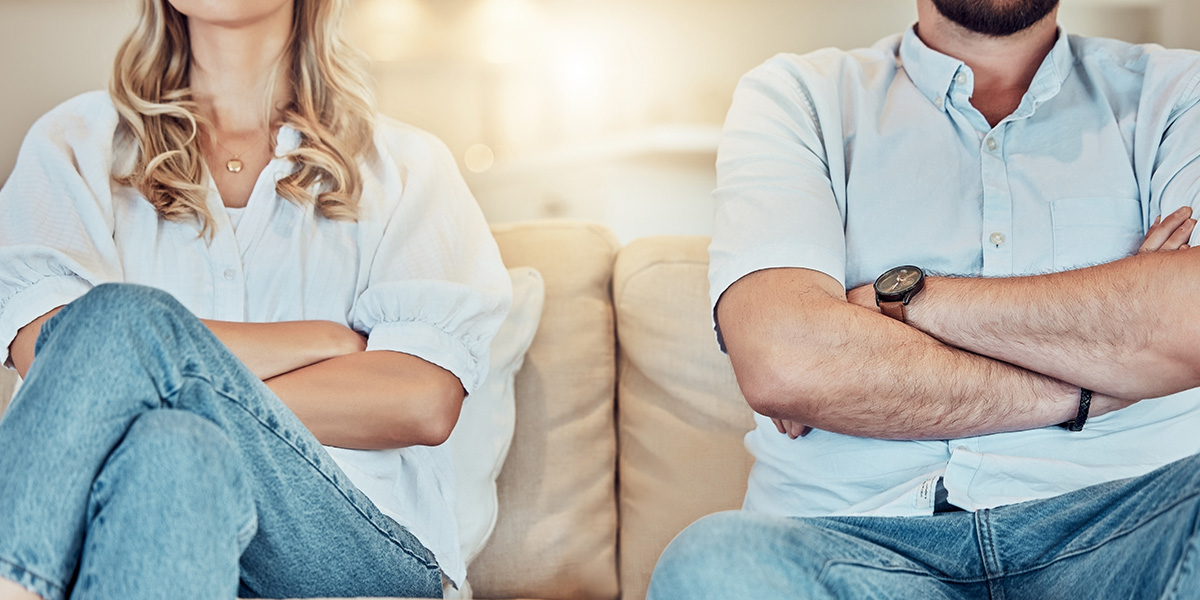 Ein Paar sitzt mit verschränkten Armen auf der Couch